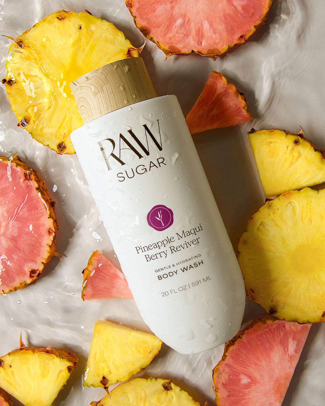 RAW Sugar body wash bottle surrounded by pineapple slices on a light background